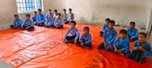 बच्चे फर्श पर तिरपाल पर पढ़ने को मजबूर